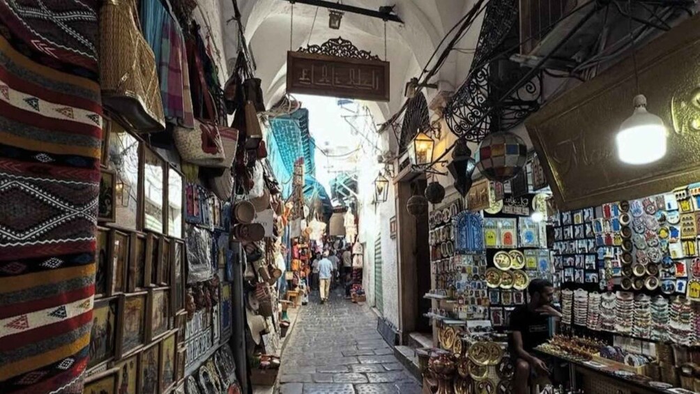 A narrow street with shops on both sides, displaying various goods. 2