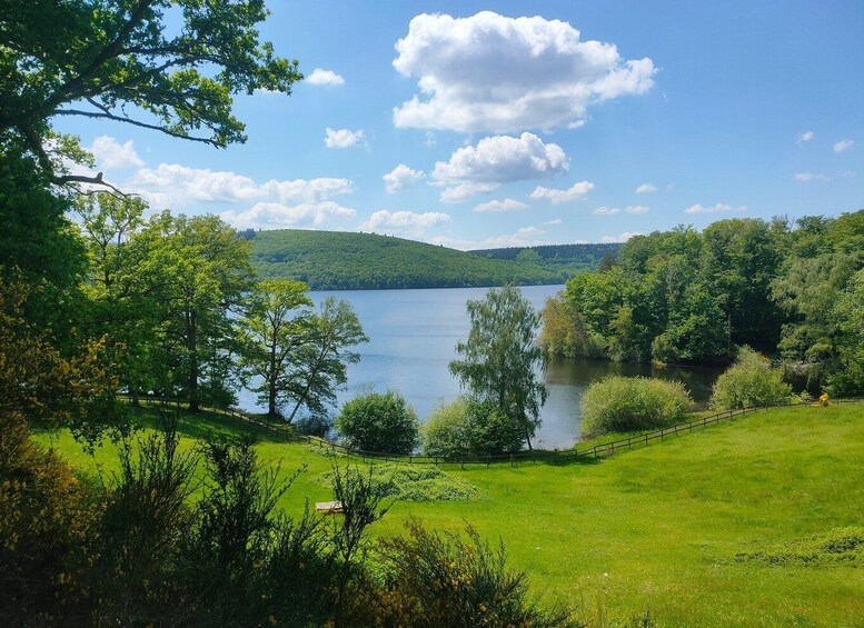 A serene lake surrounded by lush greenery and rolling hills under a clear sky. 2