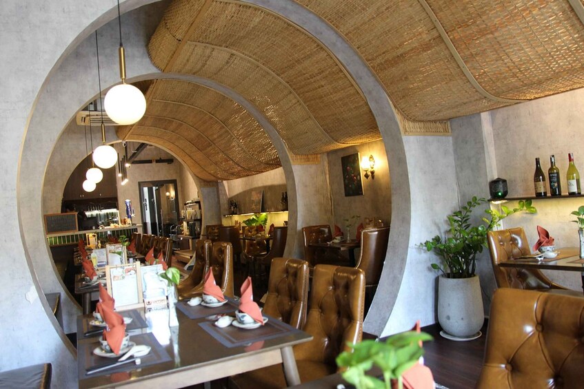An indoor restaurant with high ceilings, leather chairs, and a bar area. 1
