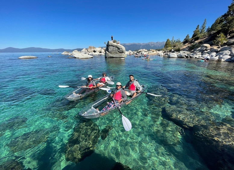 People kayaking on clear water with rocks and mountains in the background. 4