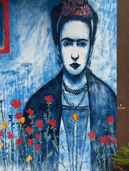 A painting of a person with a flower crown, surrounded by red and yellow flowers. 4
