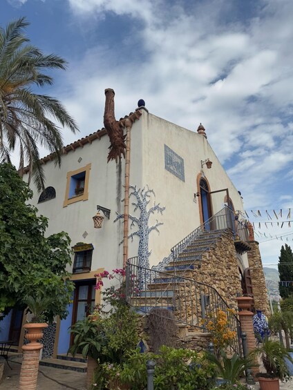 A building with a tree mural, stone staircase, and a blue door. 3