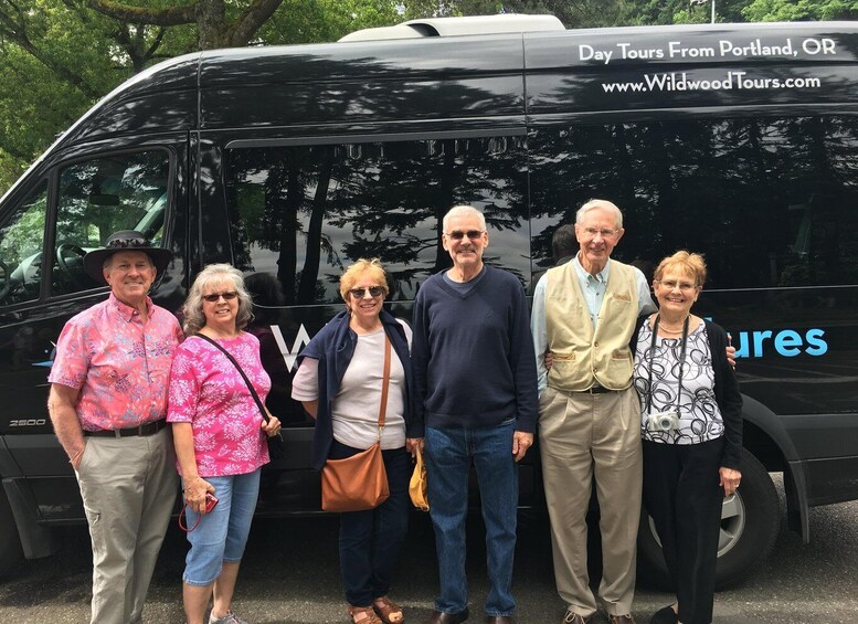 A group of people standing in front of a black van with 'Day Tours From Portland, OR' and 'www.WildwoodTours.com' on it. 5