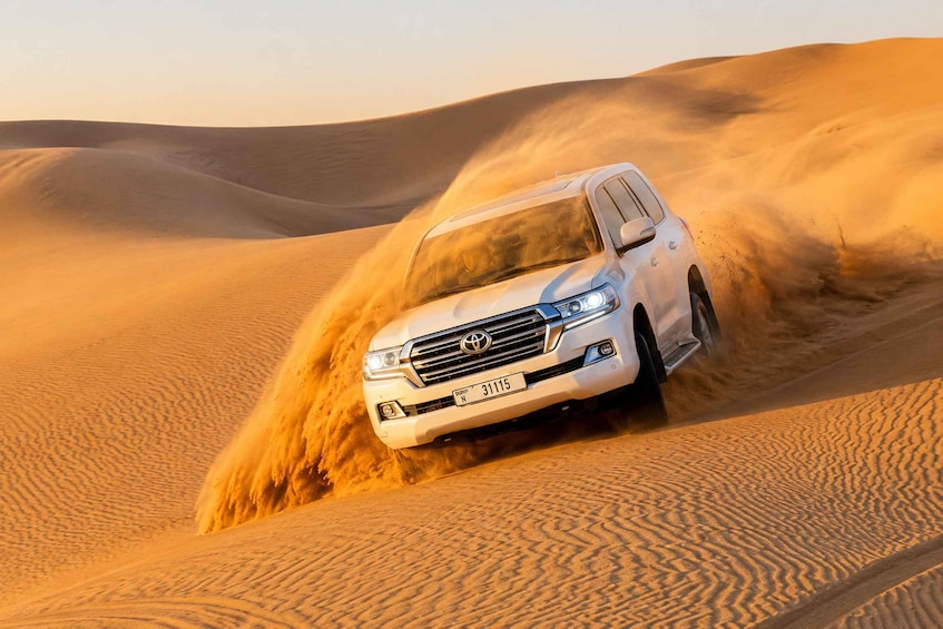 A white SUV driving through a desert with sand dunes. 2