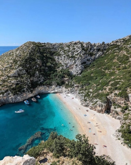 A coastal landscape with a beach, boats, and rocky cliffs. 5