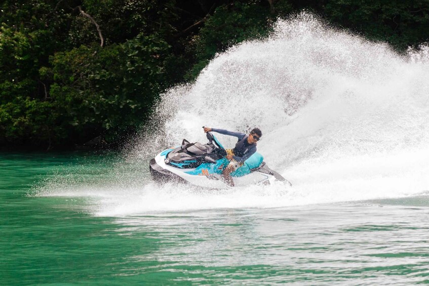 A person riding a jet ski on a body of water with a large splash behind them. 2