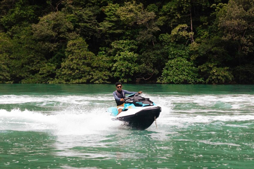 A person riding a jet ski on a body of water surrounded by dense greenery. 3