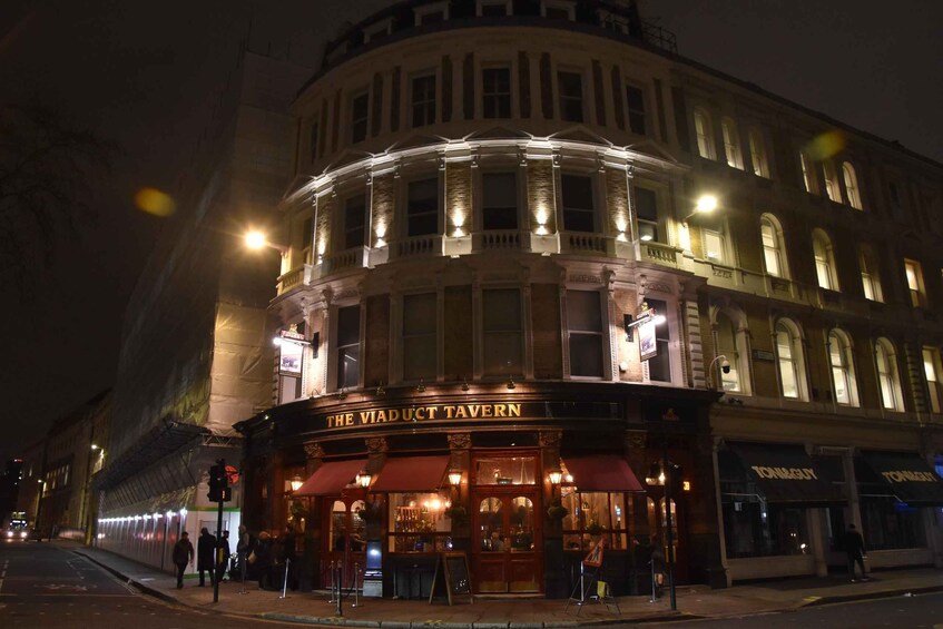 The Viaduct Tavern with illuminated signage and a classic facade. 1