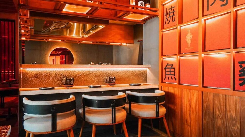 A restaurant interior with wooden accents, a counter, and three chairs. 1