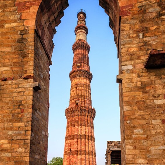 A tall, intricately carved tower with a spire, framed by arched brick structures. 4
