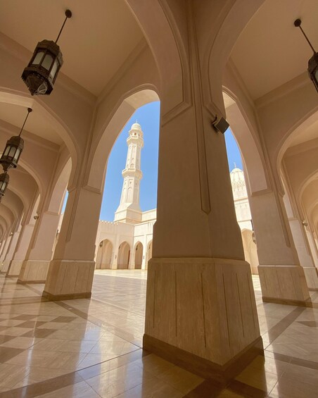 An interior corridor with arches and a view of a minaret. 1