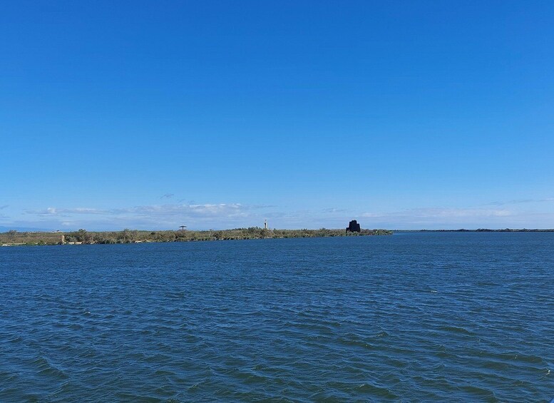 A calm sea with a distant island featuring a lighthouse and a small building. 4