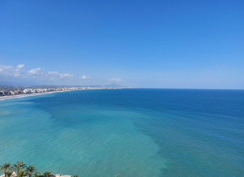 A coastal cityscape with a clear blue sky, a sandy beach, and a calm sea. 5
