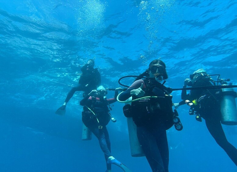 Four scuba divers underwater with bubbles rising to the surface. 3
