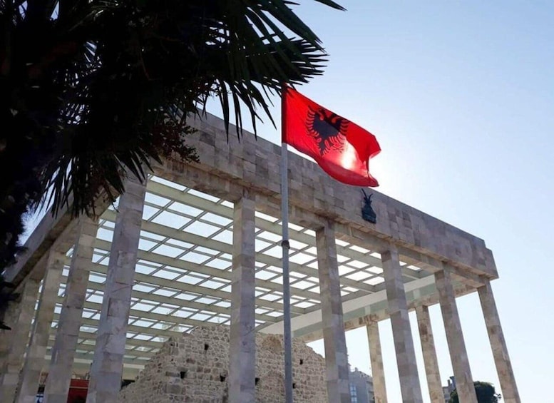 A building with a stone facade and a red flag with a black emblem. 5
