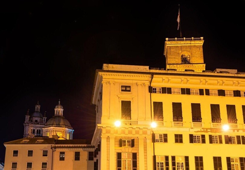 A brightly lit building with a clock tower and a dome structure in the background. 5