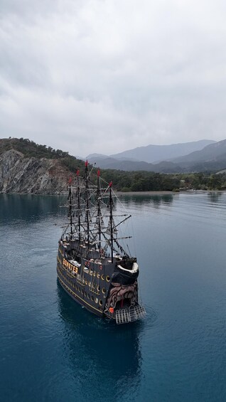 A ship named 'GONSTER' on calm waters with a mountainous backdrop. 3