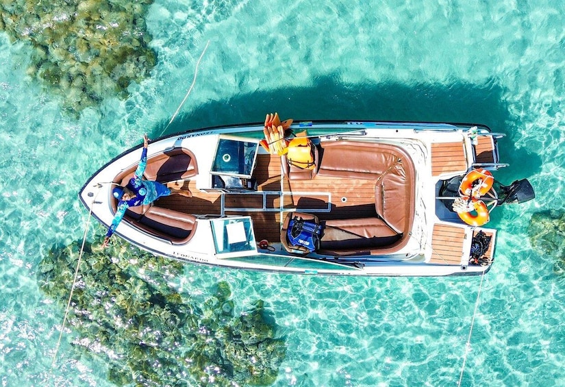 A boat with a wooden deck, a blue canopy, and a life preserver on the bow. 1