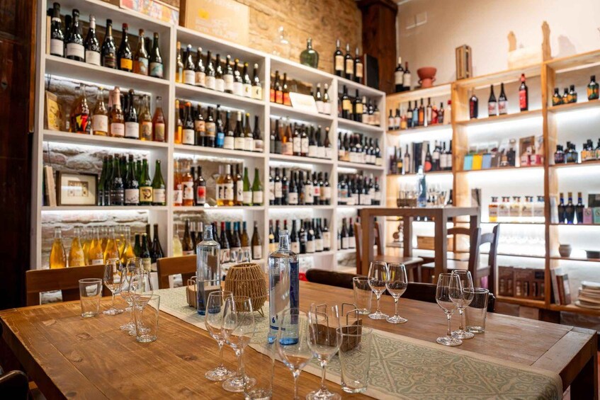 A wine cellar with shelves of wine bottles and glasses on a wooden table. 2