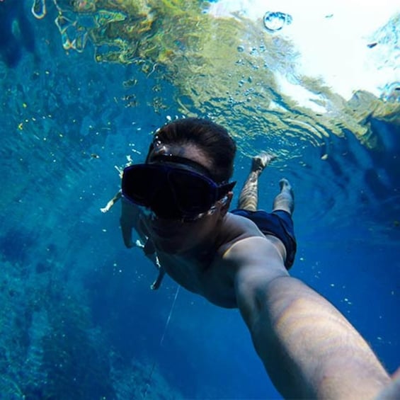 A person swimming underwater, wearing a snorkel mask and fins. 4