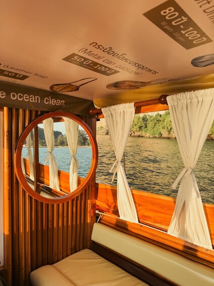 A boat interior with a view of the water, a round mirror, and curtains. 1