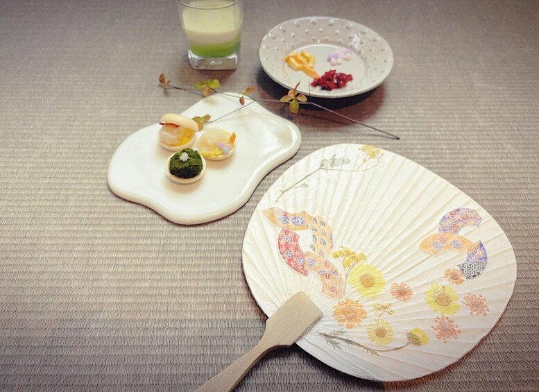 A traditional Japanese meal setup with a fan, chopsticks, and a small plate with food. 4