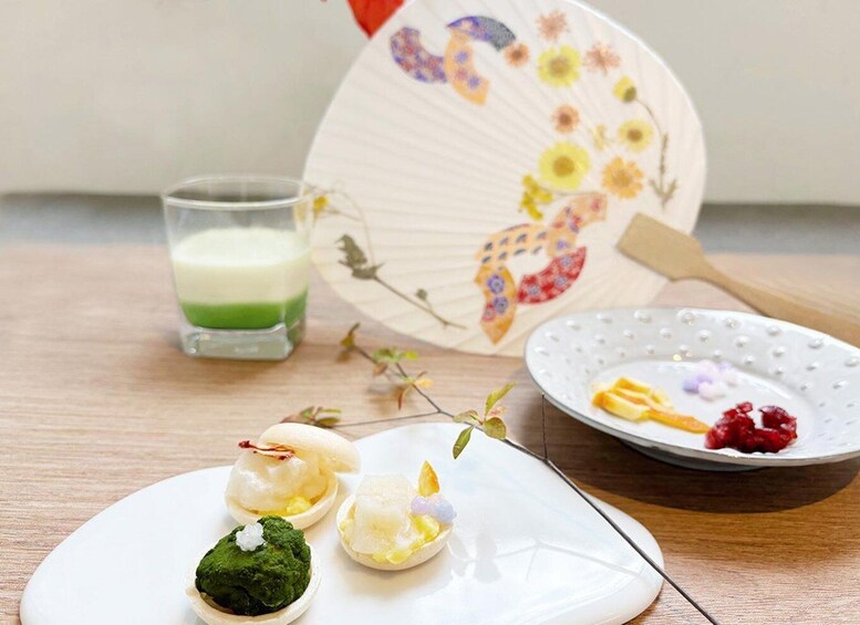 A plate with sushi, a glass of green drink, and a decorative fan. 5