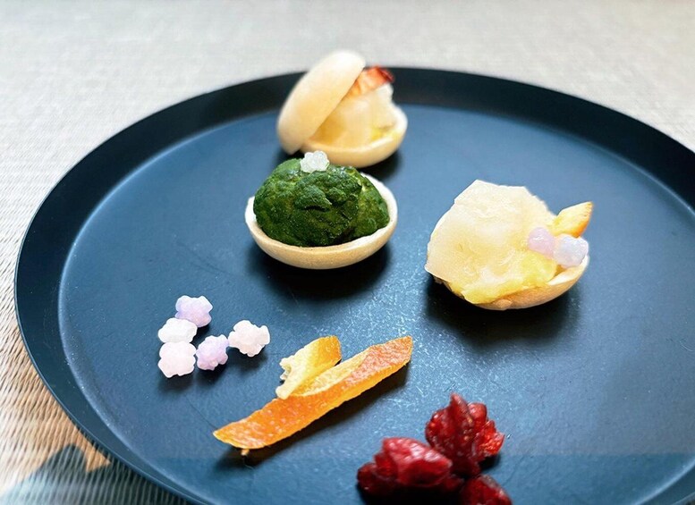 A dark blue plate with a green paste, a peeled fruit, and some berries. 3