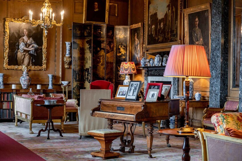 A vintage room with a grand piano, ornate furniture, and a collection of framed pictures and vases. 3