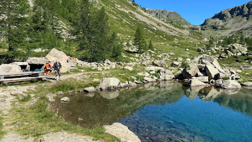 A clear mountain lake with rocky surroundings and a wooden shelter. 1