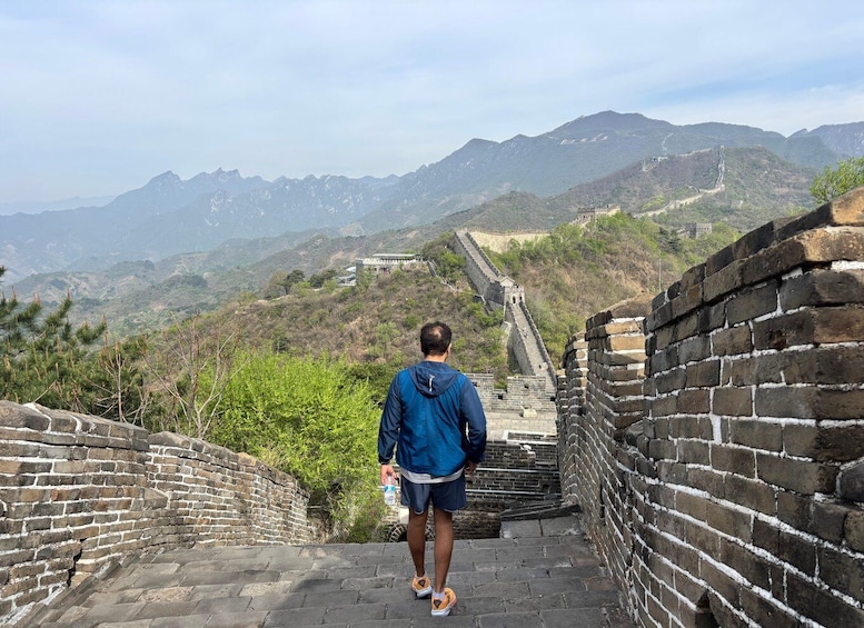 A person walking along the Great Wall of China, with mountains in the background. 3