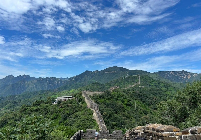 The Great Wall of China winding through a mountainous landscape under a partly cloudy sky. 1