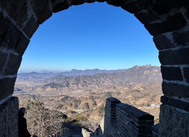 A stone archway framing a mountainous landscape with a distant town. 5