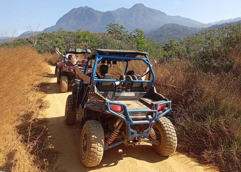 A blue off-road vehicle on a dirt path with mountains in the background. 5
