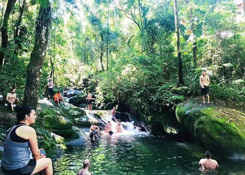 A group of people enjoying a natural water feature surrounded by lush greenery. 4