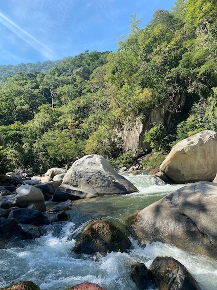 A river flowing through a rocky landscape with large boulders and dense green foliage. 4