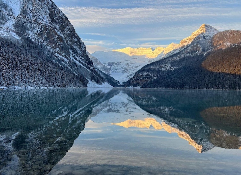 A calm lake reflecting snow-covered mountains and a clear sky. 3