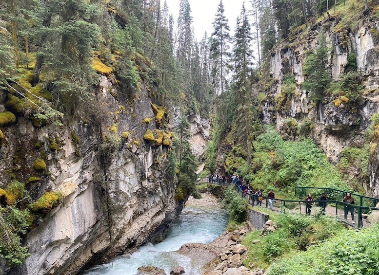 A river flowing through a canyon with a bridge and people walking on it. 5