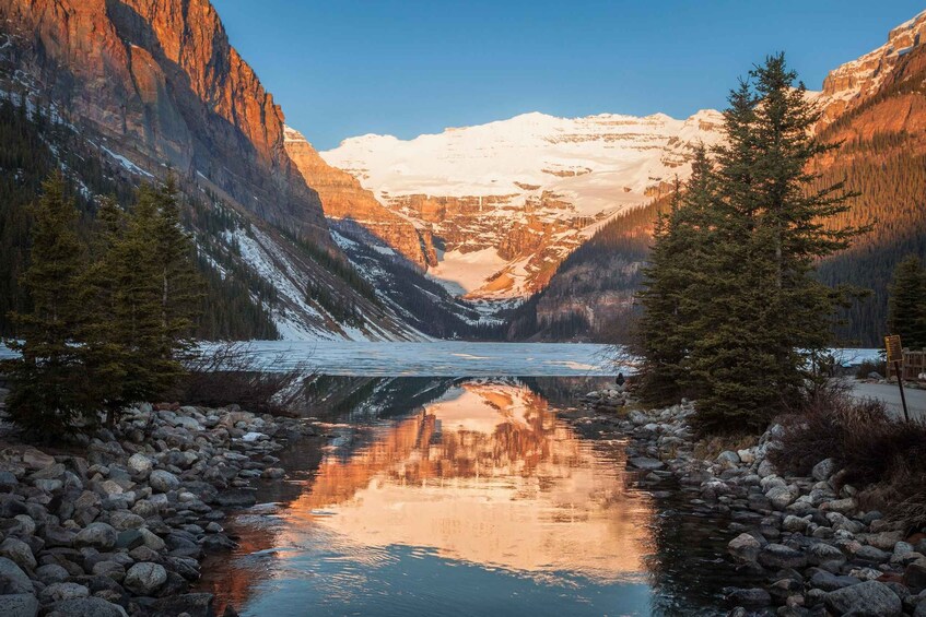 A glacial valley with a calm lake reflecting the surrounding mountains and trees. 3