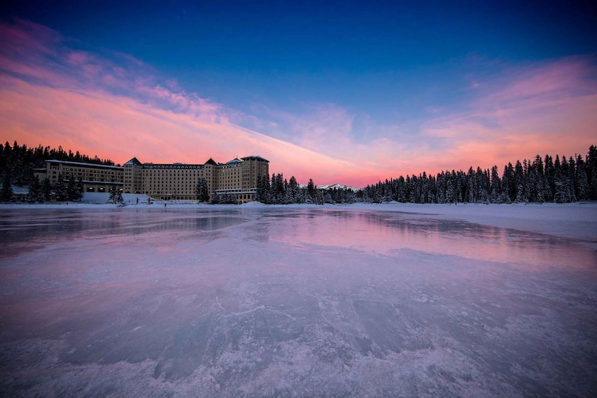 A frozen lake with a hotel and snow-covered trees in the background. 4