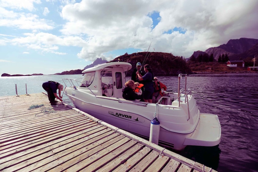 A boat docked at a pier with people on board, a mountainous landscape in the background, and a clear sky. 3