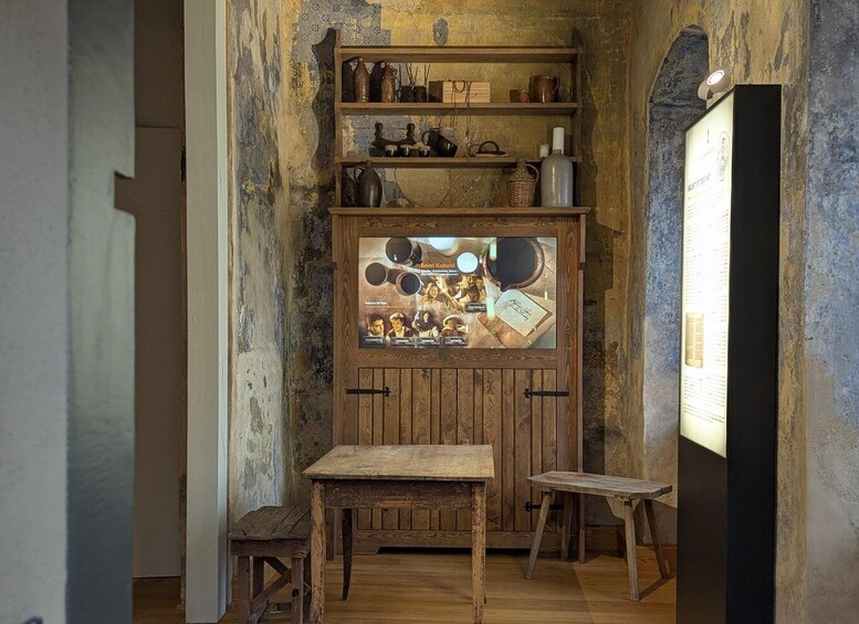 A rustic interior with wooden shelves displaying vintage items, a wooden table, and a framed poster. 2