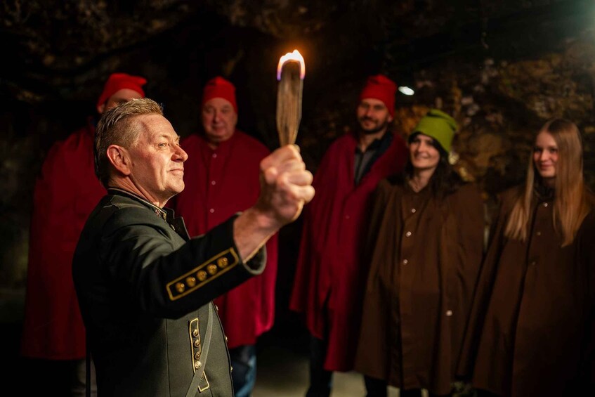 A person holding a torch with a flame, surrounded by people in red and green attire. 4