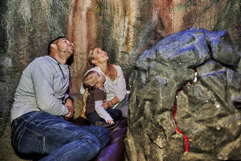 A family sitting on a cave wall with a large rock formation in the foreground. 5