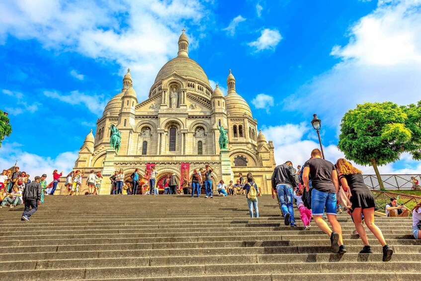 A large, ornate building with domed architecture and statues, surrounded by people ascending and descending its wide steps. 5