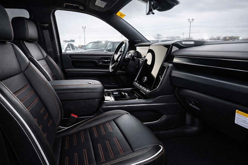 A car's interior with black leather seats, a steering wheel, and a center console. 4