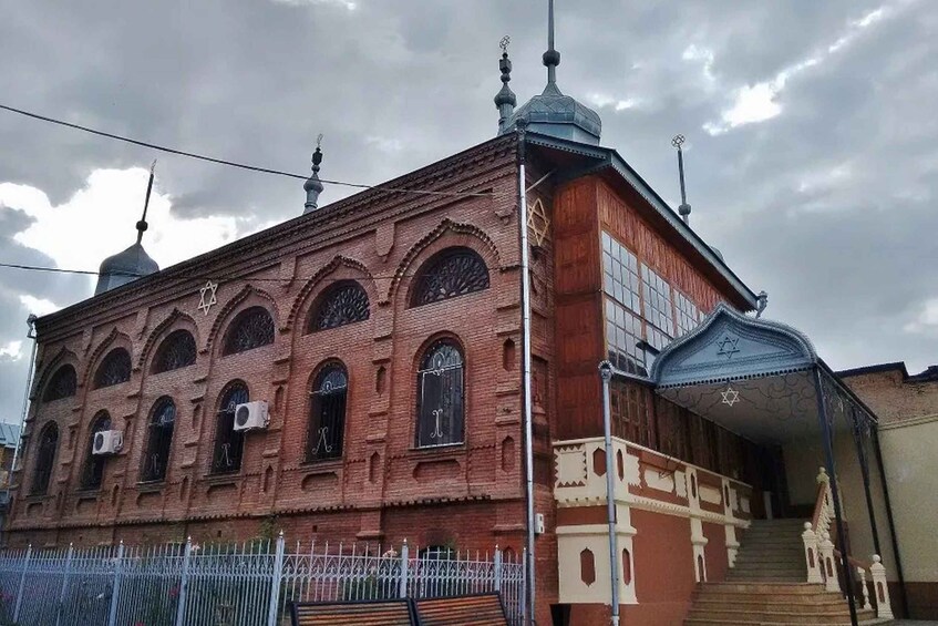 A red brick building with arched windows and a blue entrance. 5