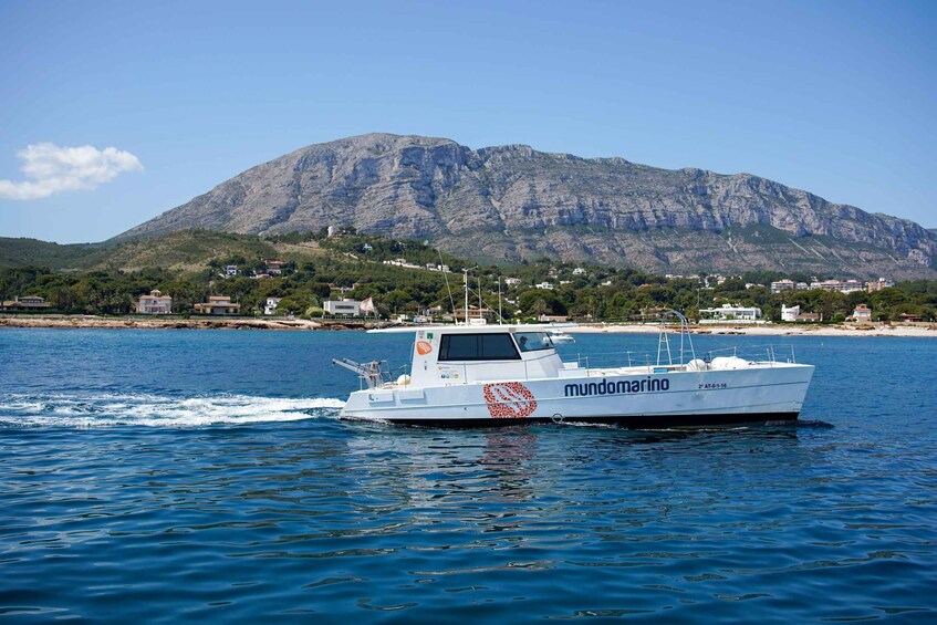 A boat named 'mundomarino' on a body of water with a mountainous landscape in the background. 2
