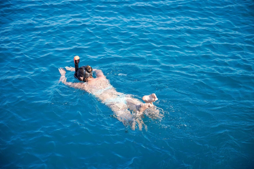A person swimming in clear blue water. 1