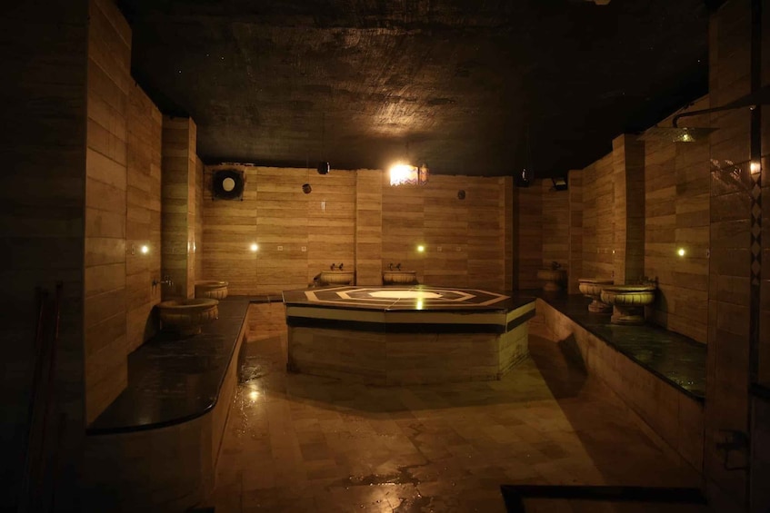 A dimly lit, stone-walled sauna with a central hot tub and two smaller tubs. 4